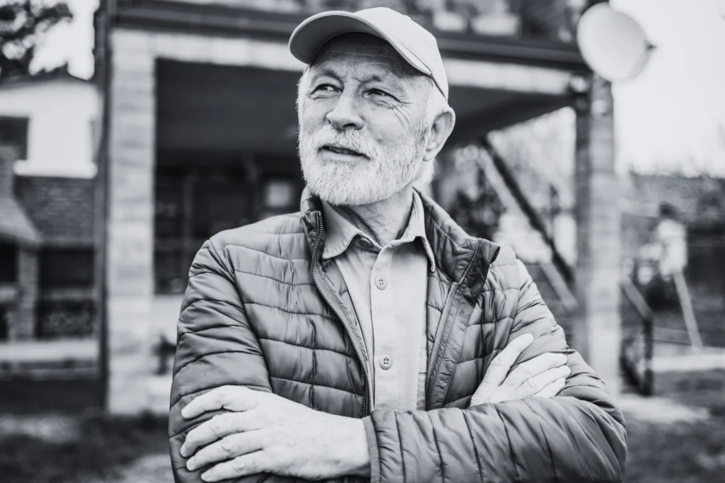 Hombre jubilado en actitud contemplativa y feliz, con los brazos cruzados