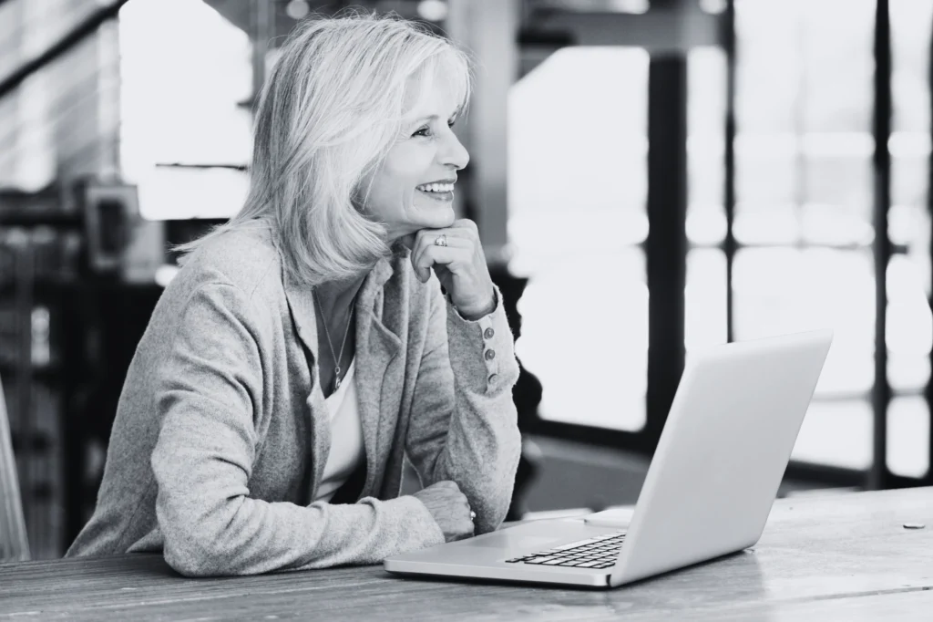 Mujer mayor trabajando con un portátil y sonriendo